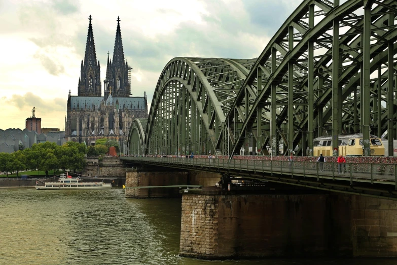 a train crossing a bridge over a river, a tilt shift photo, by Robert Zünd, shutterstock, art nouveau, behind her a gothic cathedral, istockphoto, germany. wide shot, megastructure in the background