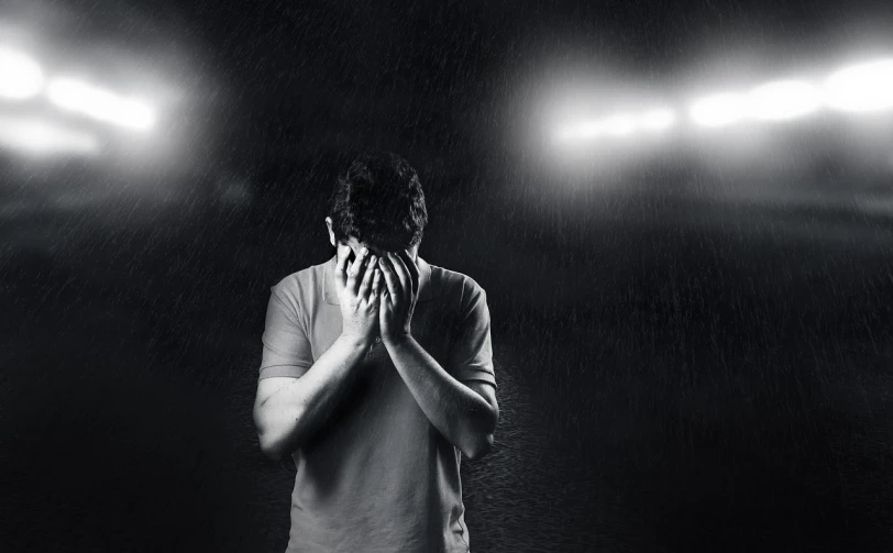 a man standing in the rain holding his hands to his face, a black and white photo, shutterstock, trauma, late night melancholic photo, interrupting the big game, abused