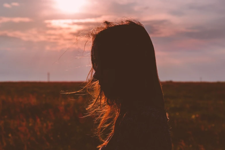 a woman standing in a field at sunset, pexels, romanticism, hair over face, unhappy, siluette, half image