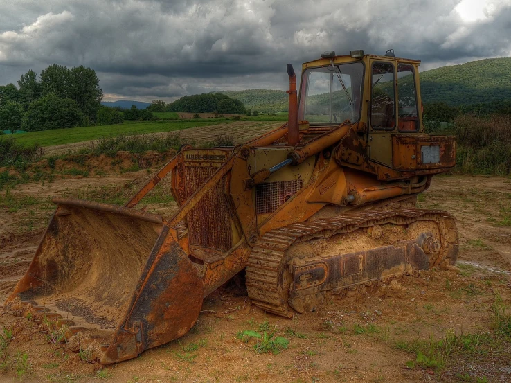 a bulldozer sitting on top of a dirt field, a portrait, by Richard Hess, pixabay, decaying rich colors!, photorealism. trending on flickr, overcast weather, seventies era