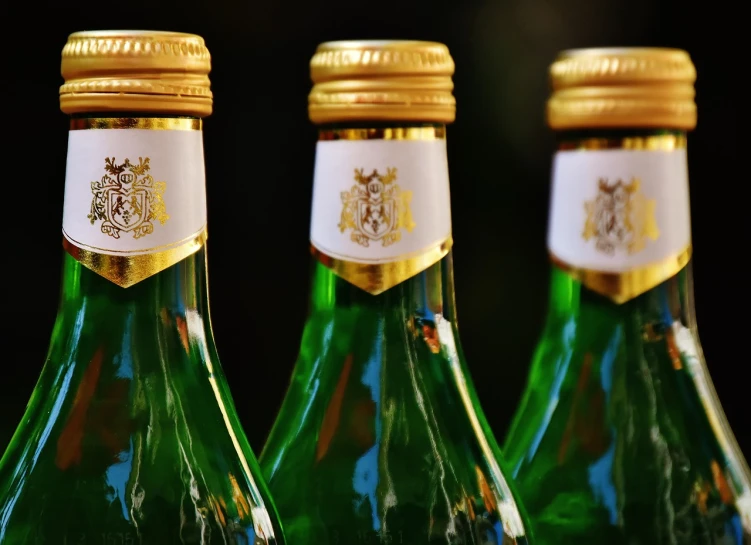 a close up of three bottles of wine on a table, a picture, pixabay, renaissance, gold and green, six packs, miniature photography closeup, pictured from the shoulders up