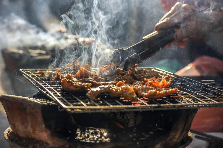 a person is cooking food on a grill, a picture, by Joe Bowler, shutterstock, intricate detail, usa-sep 20, food stall, ribs