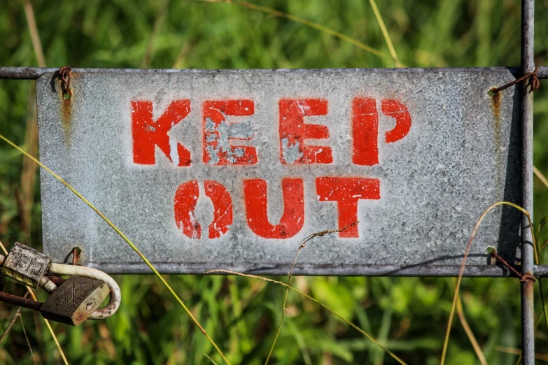 a rusted metal sign that says keep out, by Kees Bol, shutterstock, splash image, close up shot a rugged, 1940s photo, field
