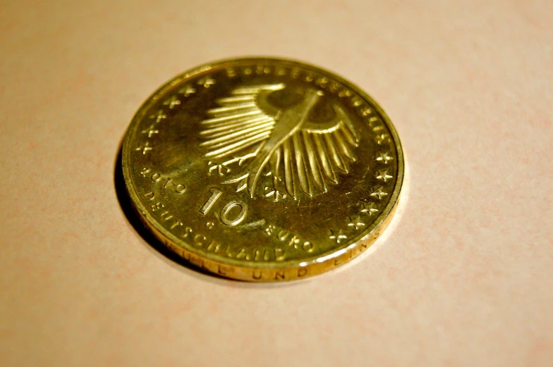 a close up of a coin on a table, by Konrad Klapheck, flickr, realistic gold, palme d'or winner, eagles, tall thin