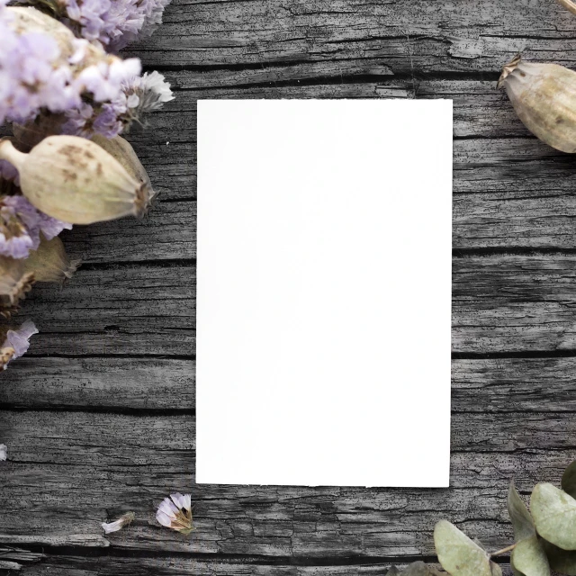 a piece of paper sitting on top of a wooden table, a picture, realism, dreamy floral background, background image, herbs and flowers, focus on card