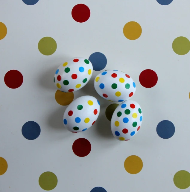 a group of polka dot eggs sitting on top of a table, a picture, inspired by Damien Hirst, flickr, full lenght view. white plastic, primary colours, hand painted, high quality product photo