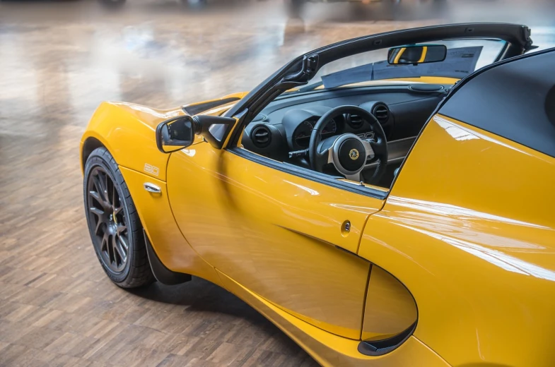 a yellow sports car sitting on top of a hard wood floor, by Richard Carline, unsplash, hyperrealism, lotus flower, wooden trim, highly detail wide angle photo, yellow and black