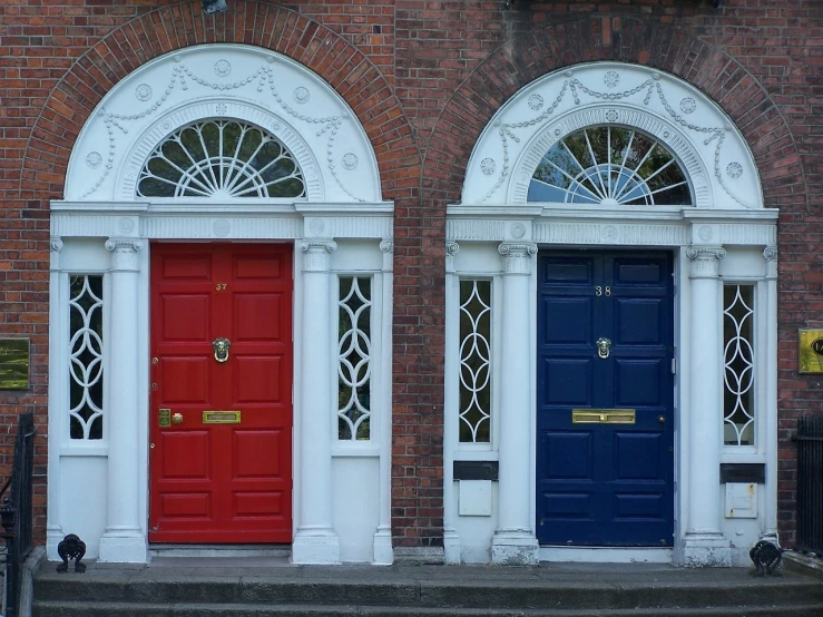 two red and blue doors on a brick building, by Joseph Henderson, pexels, ireland, doors to various bedrooms, front, trinity