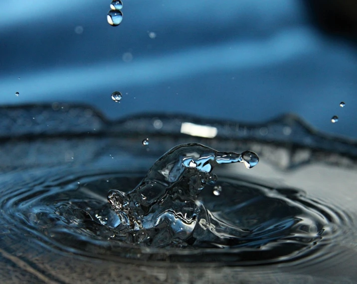 a close up of a water drop with a blue sky in the background, by Jan Rustem, flickr, water flowing through the sewer, realistic water splashes, glinting particles of ice, black-water-background