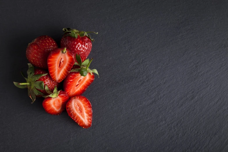 a bunch of strawberries sitting on top of a black surface, a picture, by Matthias Stom, pexels, istockphoto, next to sliced strawberries, background image, snacks