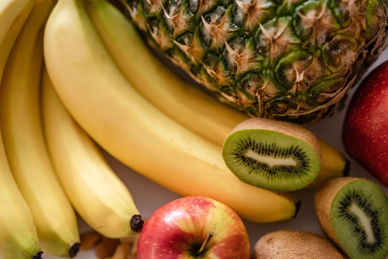 a pineapple sitting on top of a pile of fruit, a still life, by Matthias Stom, pexels, clumps of bananas, kiwi fruit, background image, istockphoto