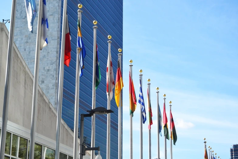 a number of flags in front of a building, a photo, by Sam Dillemans, shutterstock, united nations, manhattan, set photo, stock photo