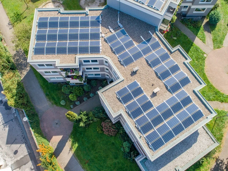 an aerial view of a house with solar panels on the roof, a photo, by Jakob Gauermann, shutterstock, bauhaus, drone photograpghy, city rooftop, stock photo