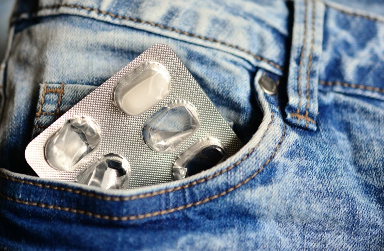 a condom in the back pocket of a pair of jeans, a picture, by Matija Jama, shutterstock, plasticien, pills, silver garment, on set, 90s photo