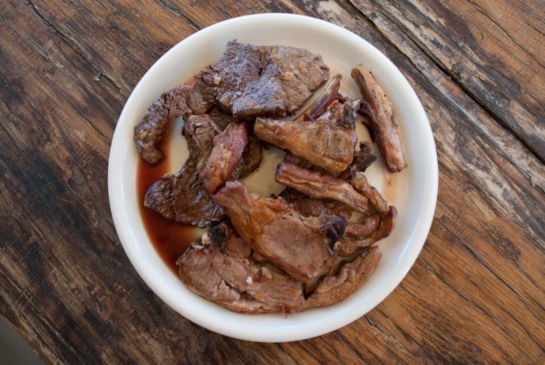 a white bowl filled with meat on top of a wooden table, mingei, very sharp photo, top down photo, hyper detailed photo, chuck roast norris