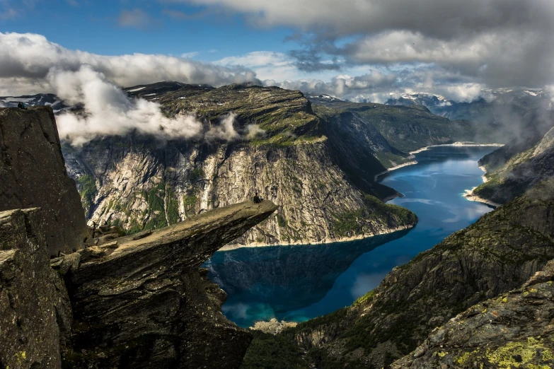 a man standing on top of a cliff next to a body of water, by Anton Lehmden, pexels contest winner, hurufiyya, norway mountains, 4k vertical wallpaper, “ aerial view of a mountain, beautiful godrays