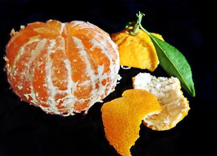 a peeled orange sitting on top of a black plate, a still life, aspic, edited, delightful, food photo