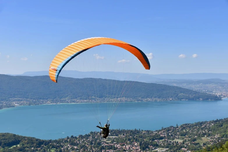 a person paragliding over a large body of water, a picture, by Bernard Meninsky, shutterstock, france, lake blue, stock photo