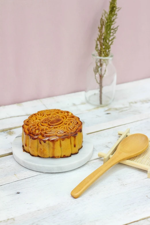 a cake sitting on top of a white plate next to a wooden spoon, inspired by Tang Di, hurufiyya, high quality product photo, professional woodcarving, pillar, festive atmosphere