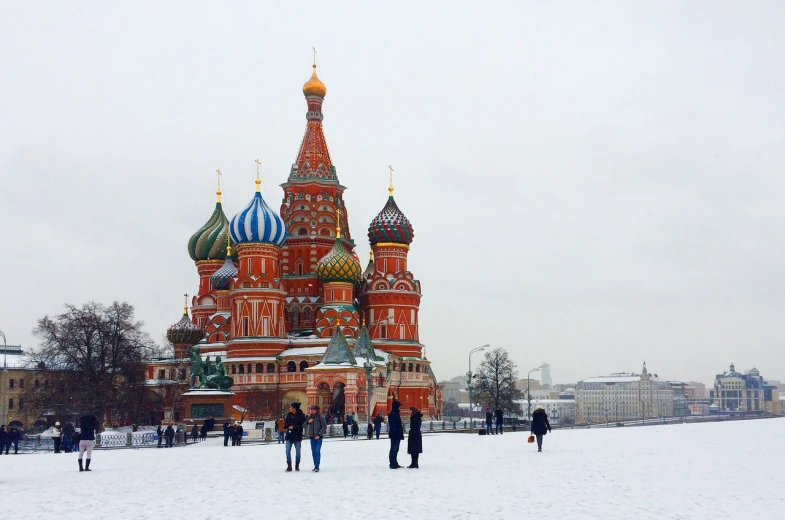 a group of people that are standing in the snow, a photo, inspired by Vasily Vereshchagin, pexels, socialist realism, cathedral in the background, reddish, a green, ground covered with snow