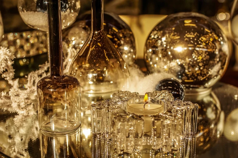 a candle sitting on top of a glass table, a still life, by Maksimilijan Vanka, pexels, baroque, vases and bottles, glass - reflecting - stars, golden glow, low detail