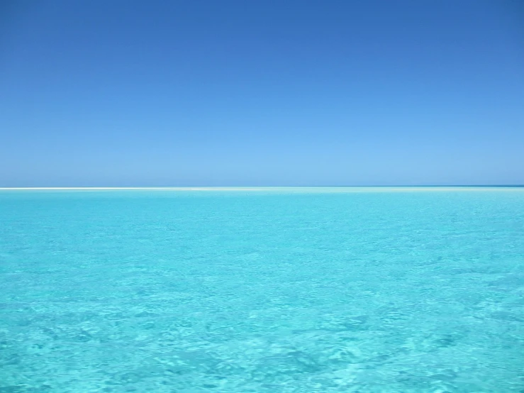 there is a large body of water in the middle of the ocean, minimalism, bahamas, cloudless blue sky, vibrant colours, beauitful