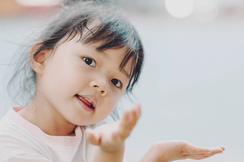a little girl that is holding something in her hand, reaching out to each other, wan adorable korean face, portrait featured on unsplash, tilt up angle