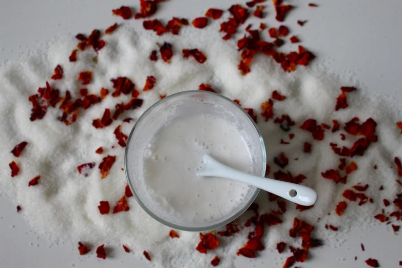 a glass of milk sitting on top of a pile of sugar, by Helen Dahm, tumblr, hurufiyya, rose petals, paprika, skincare, ooak