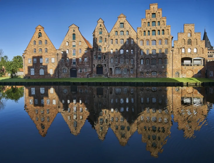 a large building sitting next to a body of water, by Hans Gude, shutterstock, brick building, many reflections, mills, high res photo