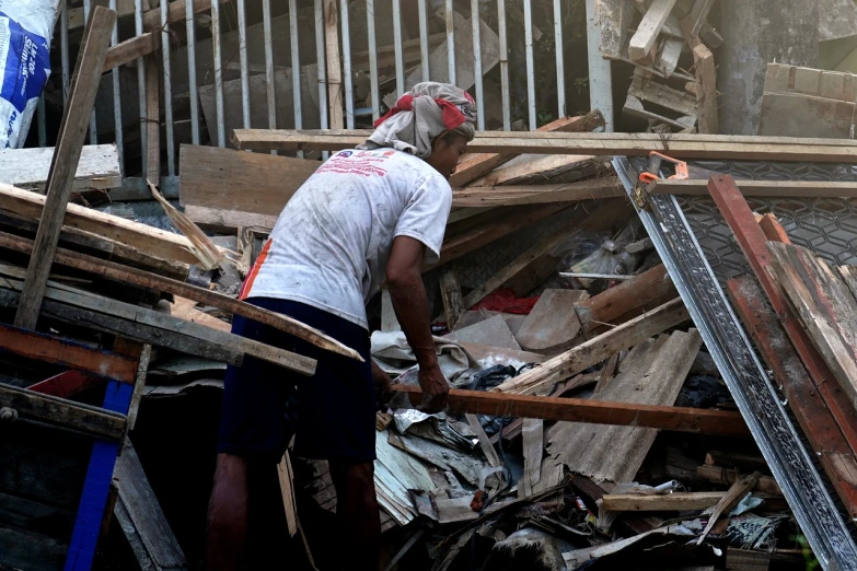 a man that is standing in front of a pile of wood, a picture, by Robbie Trevino, destroying buildings, rodrigo duterte, afp, carpenter