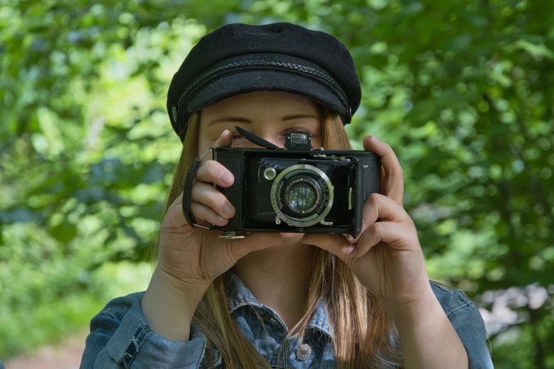 a woman taking a picture with a camera, a picture, inspired by Vivian Maier, pixabay contest winner, art photography, wearing black old dress and hat, photograph captured in the woods, teen girl, high detail portrait photo