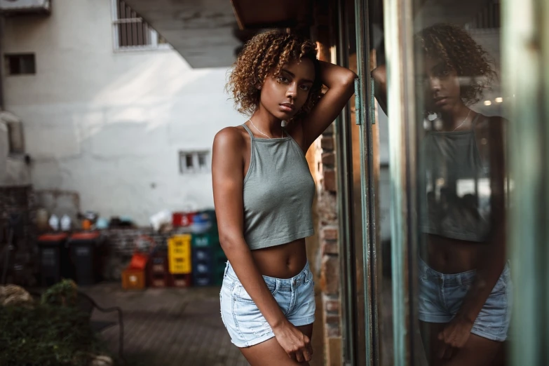 a beautiful young woman standing next to a window, a picture, by Matthias Weischer, croptop and shorts, with afro, outside a saloon, perfect composition and lighting