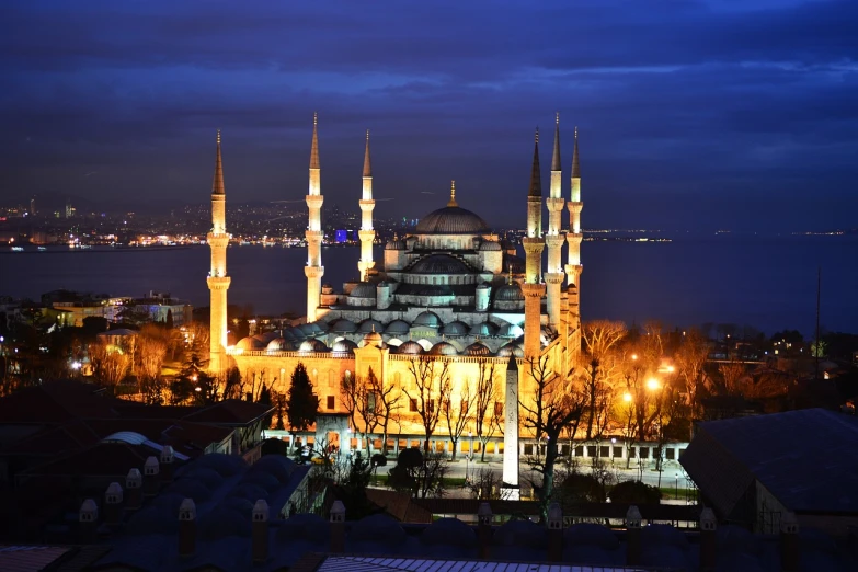 a large building sitting next to a body of water, shutterstock, hurufiyya, beautiful blue lights, ottoman sultan, majestic spires, stock photo