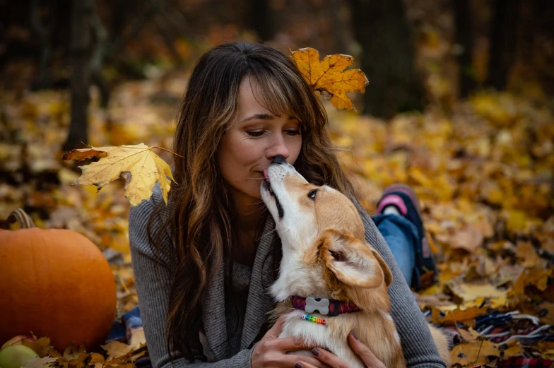a woman laying on the ground with a dog, a portrait, by Maksimilijan Vanka, shutterstock, 🍂 cute, licking out, corgi, lovely kiss
