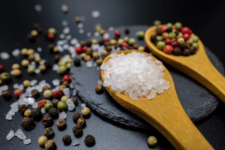 two wooden spoons filled with salt and pepper, a picture, by Josef Navrátil, pexels, renaissance, with sparkling gems on top, edible crypto, hailstorm, looking across the shoulder