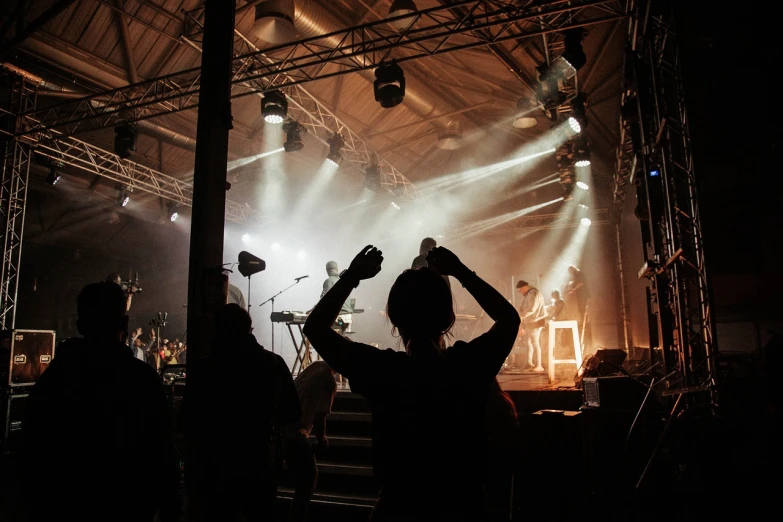 a group of people standing in front of a stage, by Tobias Stimmer, pexels, woman in a dark factory, music being played, hands up, stock photo