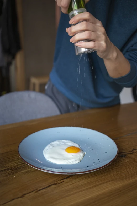 a person sprinkles salt on an egg on a plate, by Dietmar Damerau, purism, london, angled, kantoku, mikko