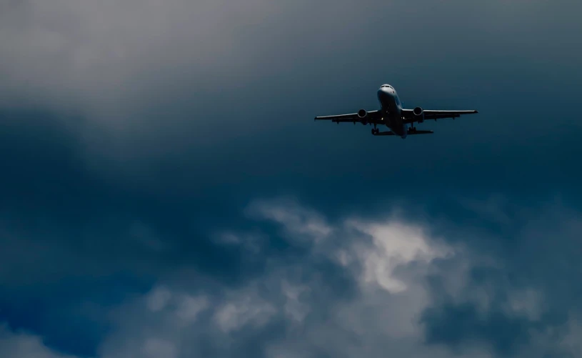 a large jetliner flying through a cloudy sky, a picture, by Hans Schwarz, pexels contest winner, black. airports, vertical wallpaper, hd footage, thumbnail