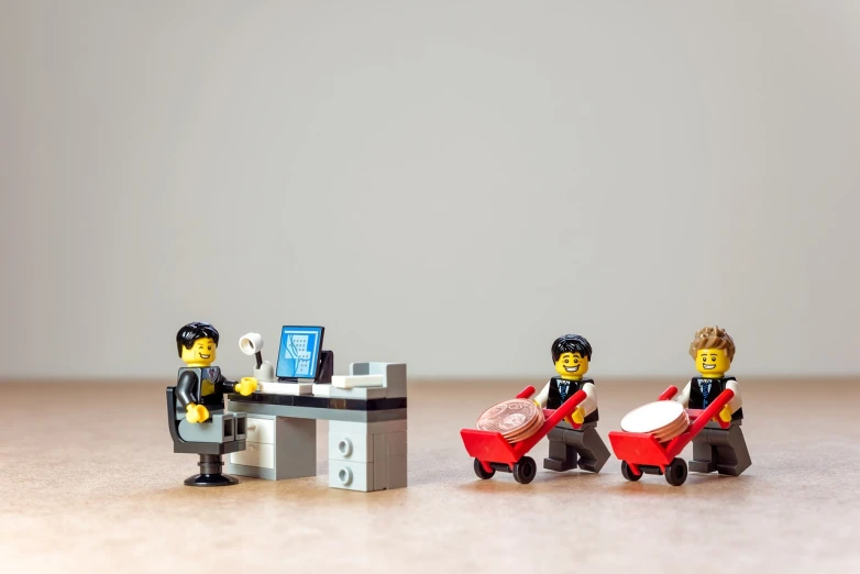 a couple of figurines sitting on top of a table, a picture, minimalism, carriage full of computers, minifigure, at checkout, corporate photo