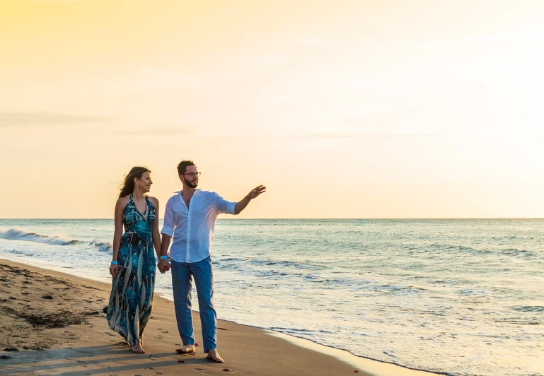 a man and a woman walking on a beach, a portrait, by Juan O'Gorman, pexels, happening, pr shoot, sunset beach, waving, commercial photography