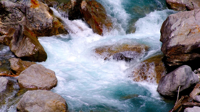 a group of large rocks sitting next to a river, a picture, hurufiyya, white water rapids, flowing teal-colored silk, dynamic!!, deep colours. ”