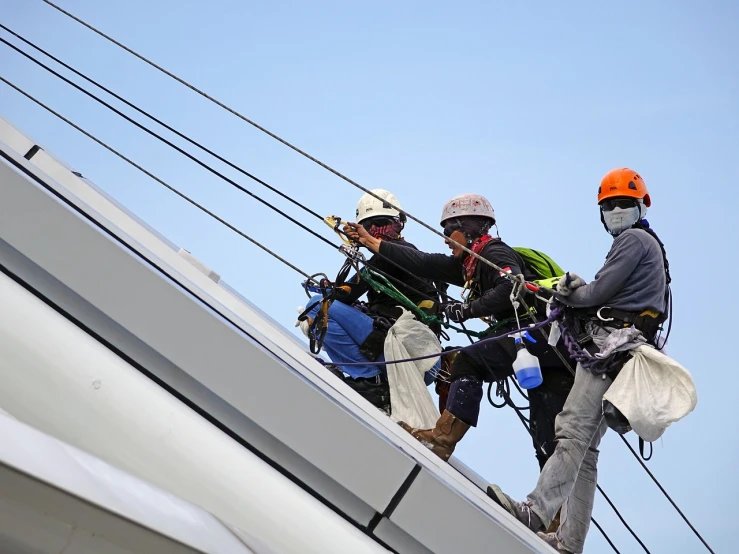 a couple of men standing on top of a building, a photo, belaying, maintenance, advanced technology, hr