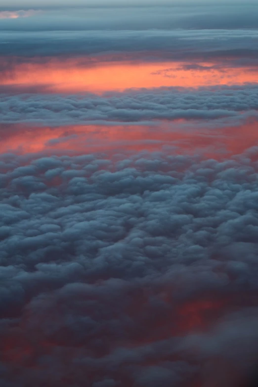 an airplane is flying high above the clouds, by Anna Haifisch, unsplash, surrealism, redpink sunset, whorl. clouds, pink and grey clouds, view from above