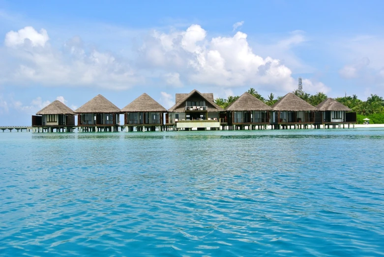 a group of huts sitting on top of a body of water, shutterstock, hurufiyya, maldives in background, 3 4 5 3 1, avalon, cottages