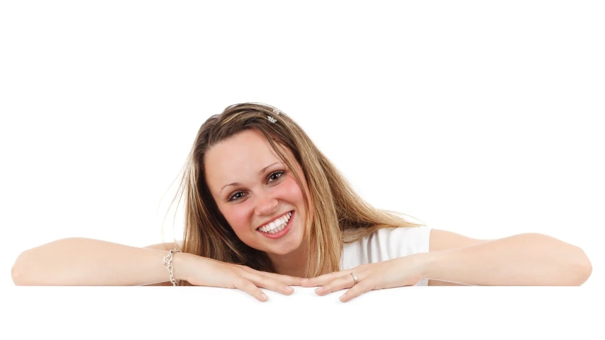 a beautiful young woman leaning over a blank sign, trending on pixabay, happening, big smile white teeth, laying down, woman with porcelain skin, holding it out to the camera