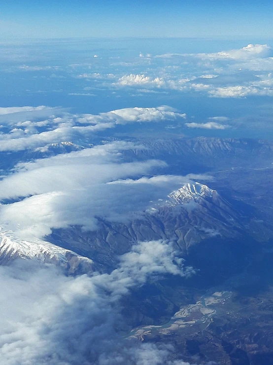 a view of mountains and clouds from an airplane, by Andrei Kolkoutine, flickr, precisionism, chilean, interesting details, idaho, wikimedia commons