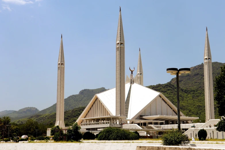 a large building with three spires in front of a mountain, modernism, islamic architecture, clean and pristine design, ap news photo, it is a place of worship