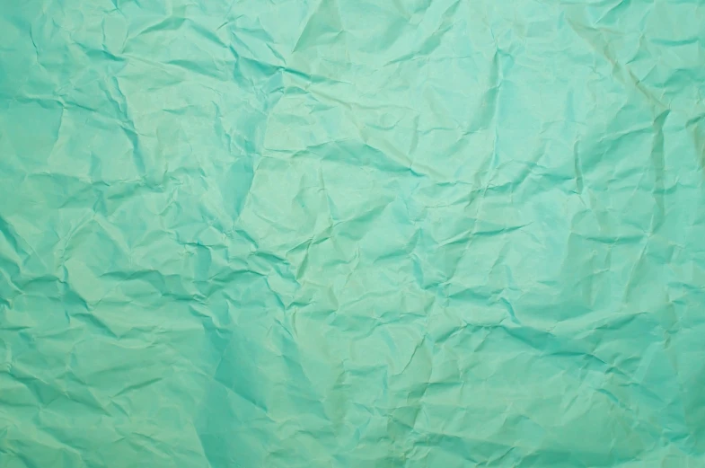 a close up of a sheet of paper on a table, inspired by Masamitsu Ōta, shutterstock, floating. greenish blue, paper crumpled texture, no gradients, background image