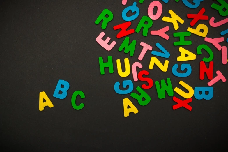 a bunch of letters sitting on top of a table, a screenshot, by Alexander Robertson, pexels, letterism, blackboard, colourfull, shape language, black colors