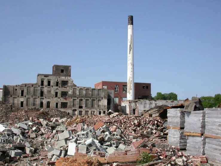 a large pile of rubble with a building in the background, by Loren Munk, flickr, chimney, tall factory, in 2 0 0 2, brick building